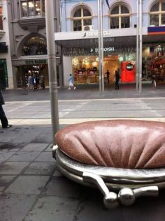 Public Purse, Bourke St Mall, Melbourne. It was commissioned in 1994 as part of an initiative by the city of Melbourne to create distinctive forms of street seating. Designed by Simon Perry, a British sculptor and academic, based in Melbourne, who is best known for his large-scale public art works for urban spaces.