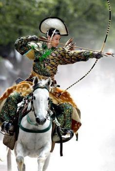 An archer dressed in traditional samurai garb displays Yabusame (archery while on horseback).  Japan.