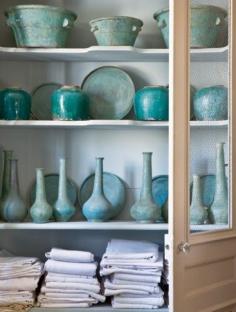 Vintage turquoise plates, urns and bottles in a French armoire