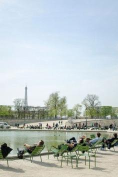 People enjoying the spring sun in the Jardin des Tuileries with the Eiffel Tower and Musée de l'Orangerie in the background