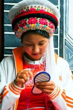 China | Bai ethnic minority young woman sewing the sole of a shoe.  Lijang, Yunan Province | © TAO Images