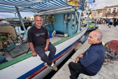Local men escape to the boats to take a break from the Sunday market in Marsaxlokk, on the island of Malta
