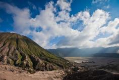 Shot from the caldera of Mount Bromo in Indonesia.  Beautiful overcast morning with light cast over that small temple below and the mountain beside.