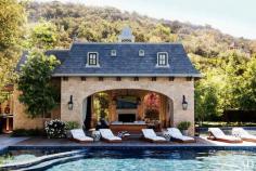 Gisele's French-inspired poolhouse with fireplace and chaise lounges on deck.
