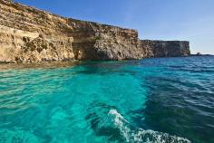 Sea cliffs of Comino rise vertically from exquisitely clear turquoise water surrounding the smallest of the Maltese Islands