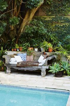 Weathered carved daybed with colorful patterned pillows.