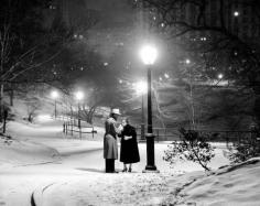 
                    
                        With the city lit up behind them, a couple wards off the cold by sharing a cigarette under a glowing street lamp in Central Park in 1957. New York City NYC
                    
                