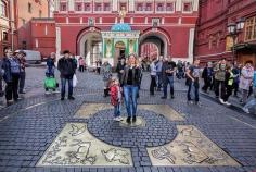 
                    
                        Visitors toss coins at Red Square entrance while standing on "Zero Kilometer," the place from which all distances in Moscow are measured
                    
                